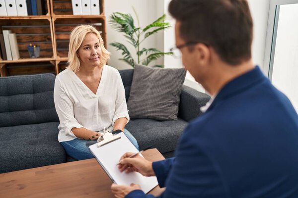 Middle age woman at psychology therapy office relaxed with serious expression on face. simple and natural looking at the camera. 