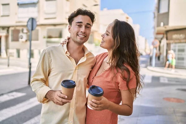 Man and woman couple drinking coffee and hugging each other at street