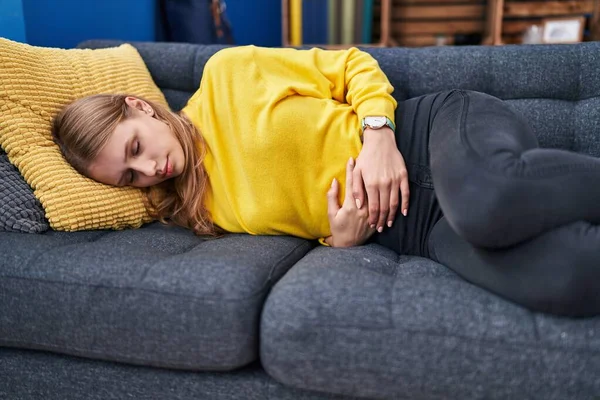 Young Blonde Woman Suffering Menstrual Pain Lying Sofa Home — Foto de Stock