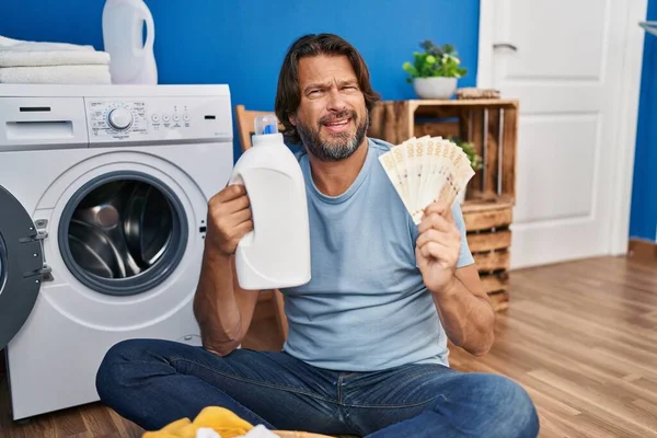 Hombre Guapo Mediana Edad Ahorrando Dinero Detergente Lavandería Expresión Despistado —  Fotos de Stock