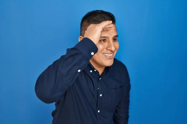 Латиноамериканец Стоящий Синем Фоне Счастлив Улыбается Глядя Вдаль Рукой Над — стоковое фото
