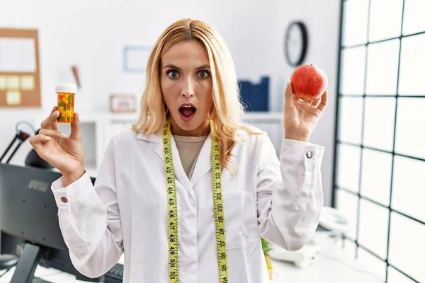 Beautiful Blonde Nutritionist Woman Holding Fat Pills Shock Face Looking — Stockfoto