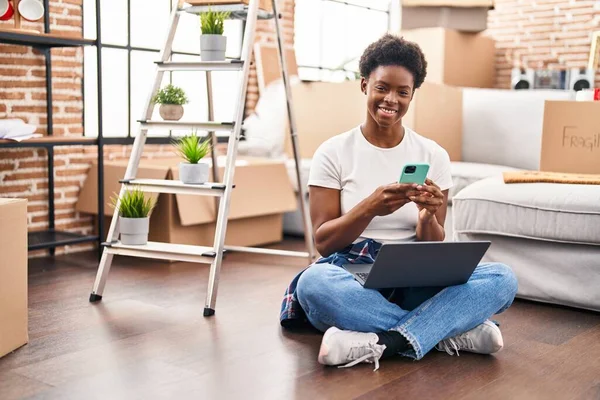 African American Woman Using Laptop Smartphone Sitting Floor New Home — стоковое фото