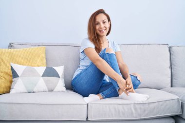 Evdeki koltukta kendinden emin gülümseyen genç bir kadın.