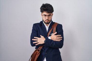 Sakallı İspanyol bir adam iş kıyafetleri giyiyor. Kış soğuğu için titriyor ve donuyor. Yüzünde üzgün ve şok ifadesi var. 