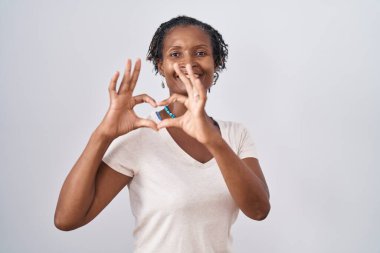 African woman with dreadlocks standing over white background smiling in love doing heart symbol shape with hands. romantic concept. 