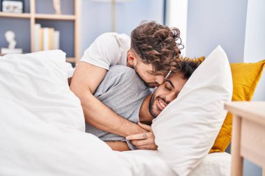 Young couple hugging each other and kissing lying on bed at bedrooom