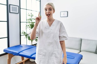 Kafkasyalı genç fizyoterapist kadın evde çalışıyor ve başarılı bir fikirle işaret ediyor. Heyecanlı ve mutlu. Bir numara.. 