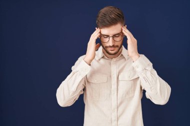 Mavi arka planda sakallı, başı ağrıyan İspanyol bir adam var. Stres yüzünden. migren ağrısı. 