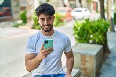 Sokakta akıllı telefon kullanan, kendine güvenen genç bir İspanyol.