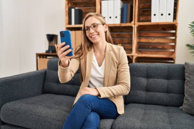 Genç sarışın kadın psikolog psikoloji kliniğinde online zihinsel danışmanlık yapıyor.