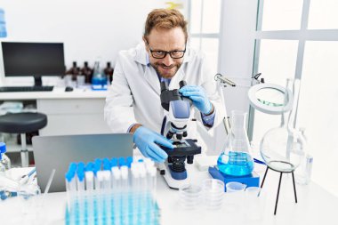 Orta yaşlı, labaratuarda çalışan bilim adamı üniforması giyen bir İspanyol.