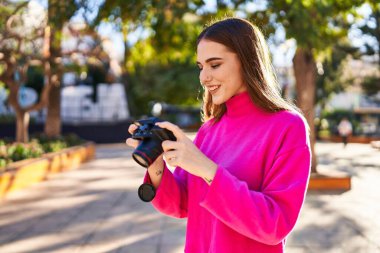 Young woman smiling confident using professional camera at park