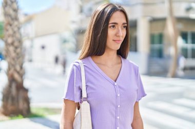 Young beautiful hispanic woman smiling confident looking to the side at street