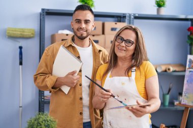 Man and woman artists smiling confident standing at art studio