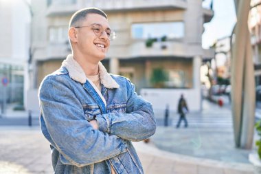 Sokakta kollarını kavuşturmuş İspanyol genç bir adam.