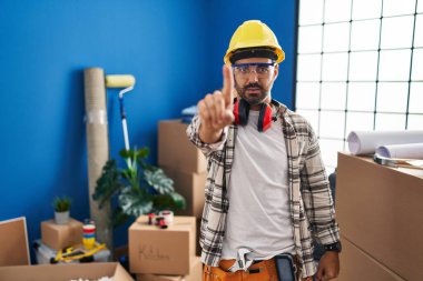 Evde çalışan sakallı, genç, ispanyol bir adam parmağını kaldırmış ve kızgın bir ifadeyle işaret ediyor. Hiç hareket göstermiyor. 