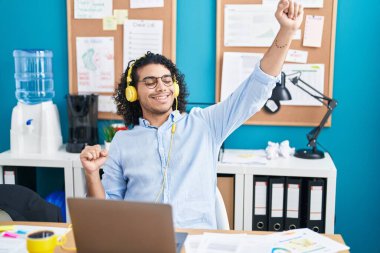 Genç Latin iş adamı ofiste müzik dinliyor.