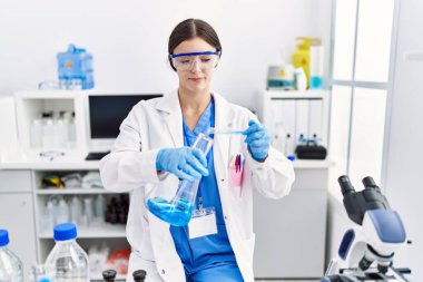 Laboratuvarda deney tüpü tutan bilim adamı üniforması giyen İspanyol genç bir kadın.