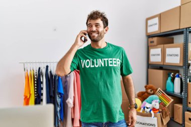 Genç İspanyol gönüllü adam gülümsüyor. Yardım merkezindeki akıllı telefondan konuşuyor..