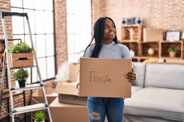 Afro-Amerikalı kadın gülümsüyor. Yeni evinde kendine güveni tam bir paket tutuyor.