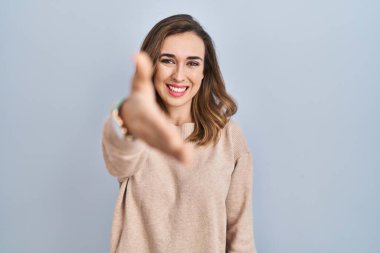 İzole edilmiş arka planda duran genç bir kadın dostça gülümseyerek selamlaşma ve selamlama olarak el sıkışır. başarılı iş. 