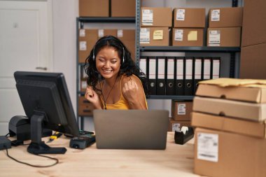 Young asian woman working at small business ecommerce wearing headset very happy and excited doing winner gesture with arms raised, smiling and screaming for success. celebration concept. 