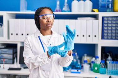 Bilim adamı üniforması ve eldiven laboratuarı giyen Afrikalı Amerikalı kadın.