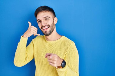 Mavi arka planda durup gülümseyen İspanyol bir adam telefonla konuşuyor ve seni işaret ediyor. Ara beni.. 