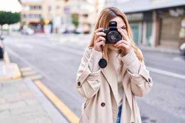 Young blonde woman susing professional camera at street