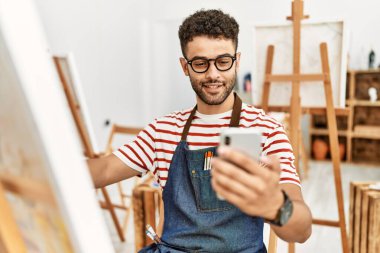 Sanat stüdyosunda akıllı telefon çizimi yapan genç bir Arap sanatçı..