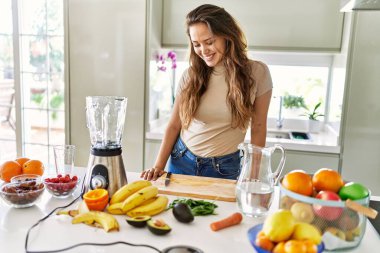 Genç, güzel İspanyol kadın mutfakta sebze suyu ve blender hazırlıyor.