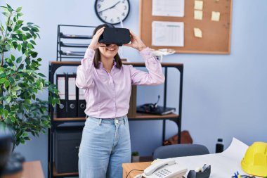 Young hispanic woman architect using virtual reality glasses at office