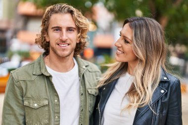 Erkek ve kadın bir arada durarak gülümsüyor.