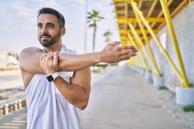 Güneşli bir günde dışarıda çalıştıktan sonra kollarını esneten İspanyol bir adam.