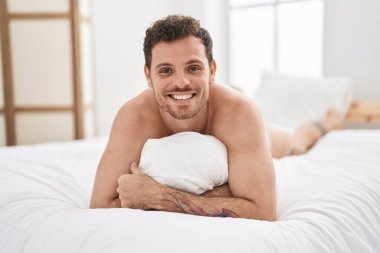 Genç İspanyol adam yatak odasında yastığa sarılıyor.