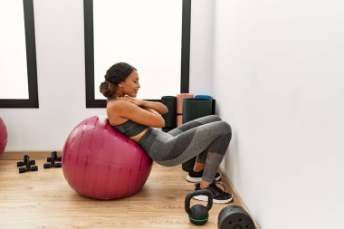 Genç Latin kadın gülümsüyor spor merkezinde formda top kullanan kendine güvenen karın kasları.