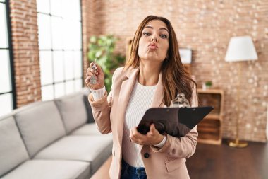 Genç esmer kadın elinde yeni evin anahtarları olan emlakçı olarak çalışıyor. Kameraya bakıyor ve öpüşüp koklaşıyor. Sevimli ve seksi. aşk ifadesi. 