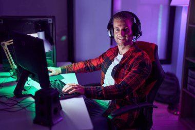 Genç beyaz adam oyun odasında bilgisayar kullanarak video oyunu oynuyor.