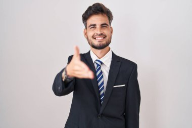 İş elbisesi ve kravat takan İspanyol asıllı genç adam selamlama ve hoş geldin demek için gülümseyerek tokalaşıyor. başarılı iş. 