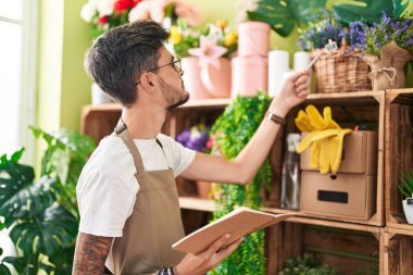 Çiçekçide gevşek bir ifadeyle not defteri okuyan İspanyol bir çiçekçi.