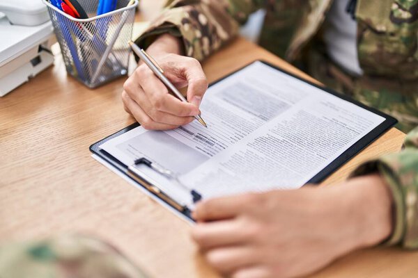 Young hispanic man army soldier signing contract at office