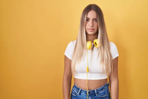 Young Blonde Woman Standing Yellow Background Wearing Headphones Relaxed Serious — Zdjęcie stockowe