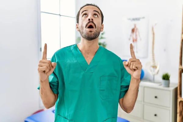 Young Physiotherapist Working Pain Recovery Clinic Amazed Surprised Looking Pointing — Stok fotoğraf