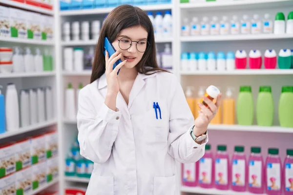 Mulher Branca Jovem Farmacêutico Segurando Pílulas Garrafa Falando Smartphone Farmácia — Fotografia de Stock