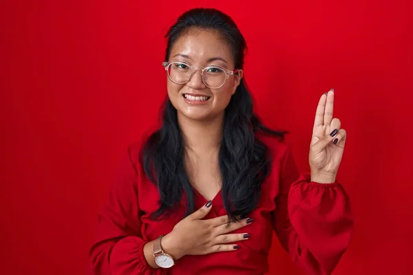 Asian Young Woman Standing Red Background Smiling Swearing Hand Chest — Stock Photo, Image
