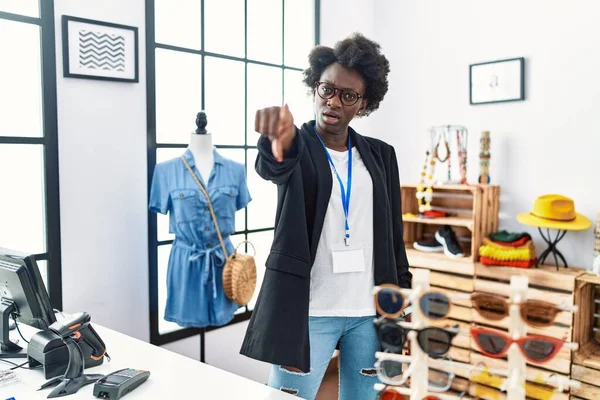 African young woman working as manager at retail boutique pointing displeased and frustrated to the camera, angry and furious with you