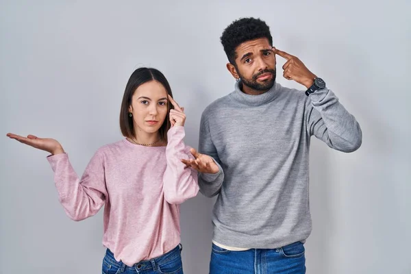 Young Hispanic Couple Standing Together Confused Annoyed Open Palm Showing — Fotografia de Stock