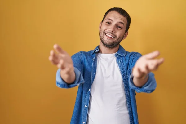 Hispanic Man Standing Yellow Background Smiling Cheerful Offering Hands Giving — Stok fotoğraf