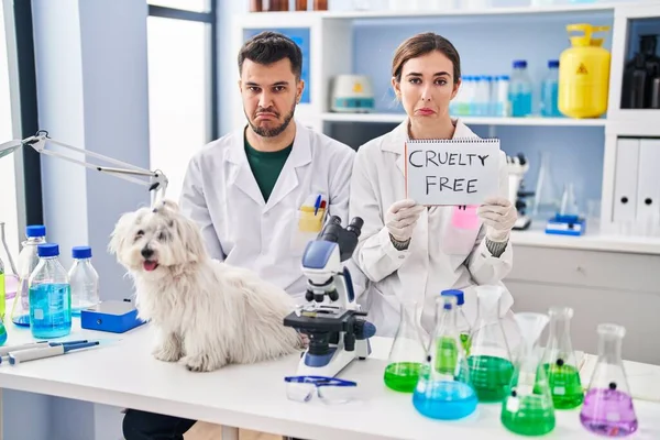 Young hispanic people working at scientist laboratory with dog depressed and worry for distress, crying angry and afraid. sad expression.